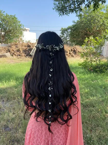 An open hairstyle with a delicate waterfall braid and baby's breath. This is a perfect look for a daytime event like a Mehendi or Haldi.