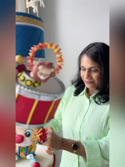 A behind-the-scenes shot of me putting the finishing touches on the giant carnival cake, showing the scale and intricate detail involved in such a large project.