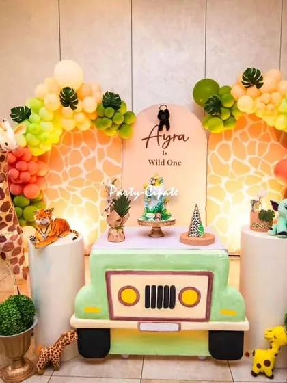 A 'Wild One' safari party is always a favorite. I focus on creating a fun and friendly jungle atmosphere with life-sized animal props like a giraffe and elephant, a custom jeep-shaped table for the cake, and balloon garlands that match the safari color palette.