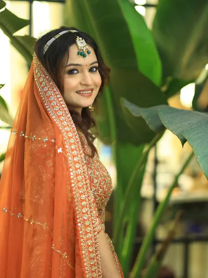 A beautiful portrait of a model in an orange lehenga, showcasing a look perfect for a bridesmaid or wedding guest.