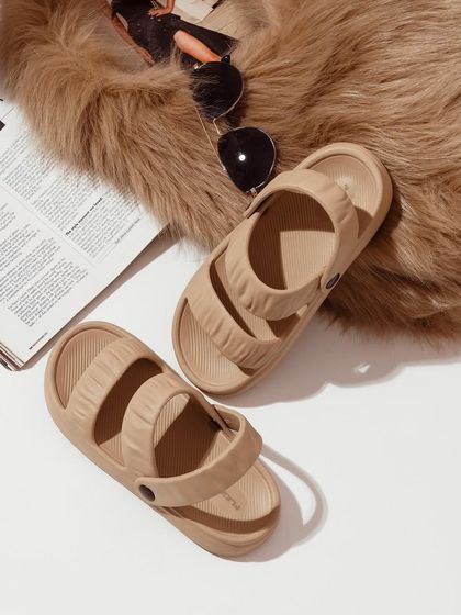 A flat-lay lifestyle shot, pairing these beige sandals with a magazine, sunglasses, and a faux fur rug to create a chic, fashionable mood.