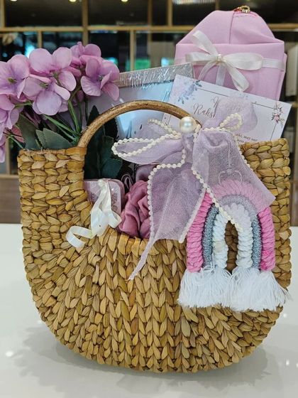 A side view of the beautiful Kauna basket hamper, decorated with lilac flowers and a pearl-studded bow.