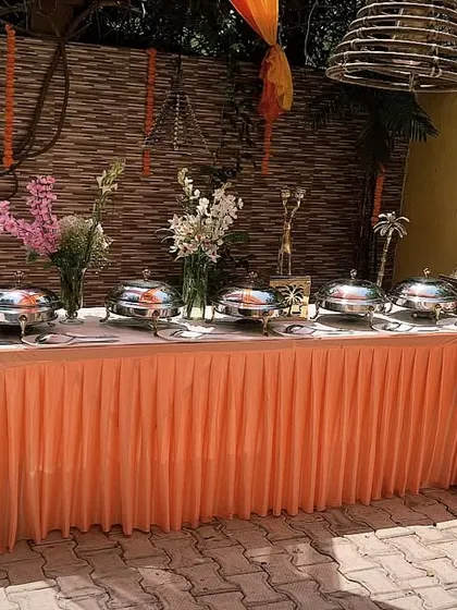 A beautifully presented buffet layout for a private event of 50 guests. The peach-colored linens and rustic backdrop create a warm and inviting feel.