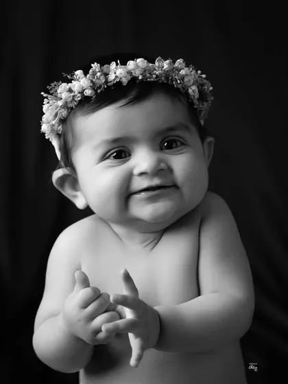 A timeless black and white portrait that focuses on pure emotion. The simplicity of this style highlights her adorable expression and clapping hands. These classic baby portraits are designed to be cherished for generations, capturing the soul of your child without distraction.