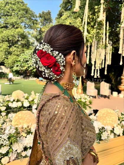 A detailed shot of the mother of the groom's hairstyle. The classic bun adorned with fresh red roses and baby's breath adds a touch of timeless elegance to her look.