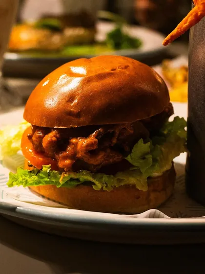 A classic buffalo chicken burger from Mollie's Motel & Diner. The lighting gives the brioche bun a beautiful sheen, making it look incredibly soft and appealing.