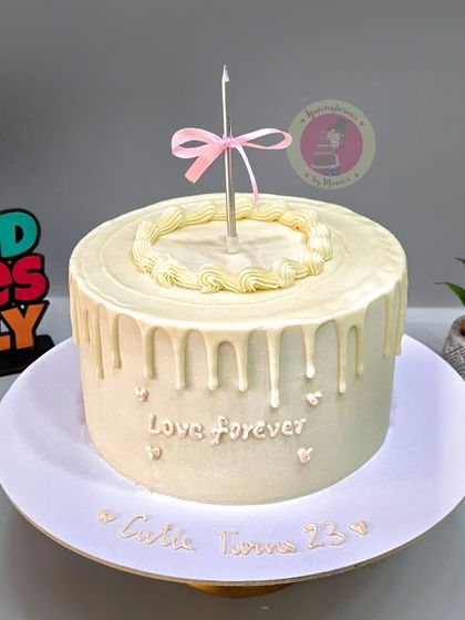 A simple and elegant vintage cake with a white chocolate drip and a single candle for a 25th birthday.