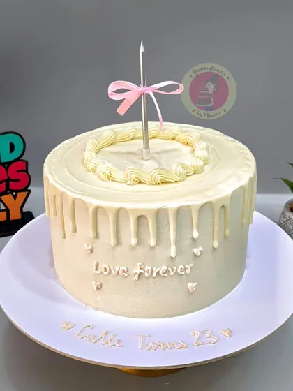 A simple and elegant vintage cake with a white chocolate drip and a single candle for a 25th birthday.
