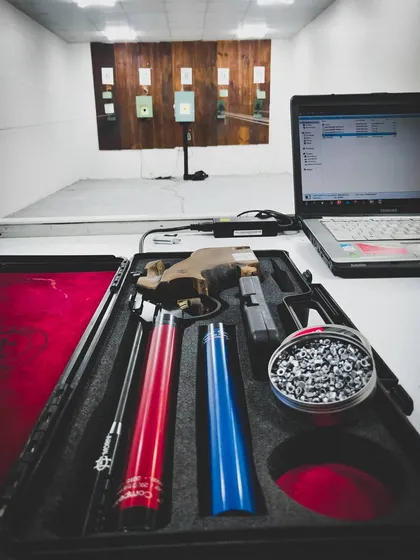 A look at the professional equipment used in my sessions, including a cased air pistol, interchangeable barrels, and a tin of pellets, with the 10m range ready in the background.