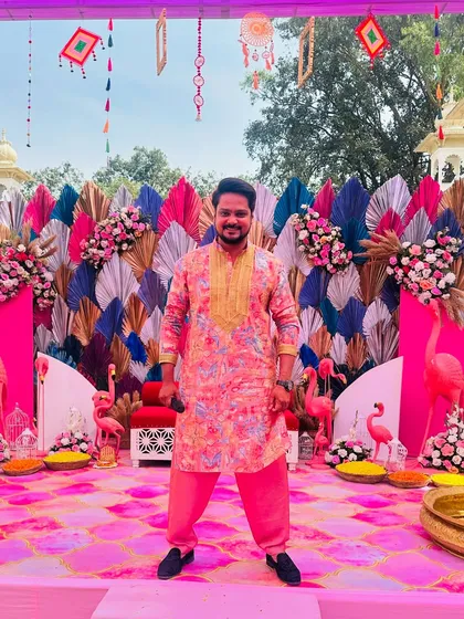 Posing against a vibrant, flamingo-themed Haldi decor. The colorful and festive atmosphere of daytime events is something I truly enjoy.