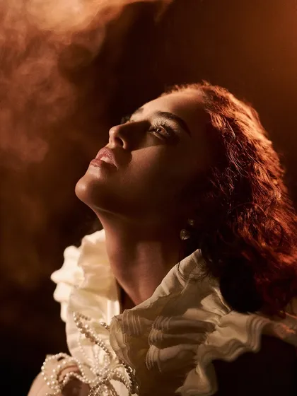 Capturing atmosphere is key. In this shot from the 'Velvet Shadows' series, I introduced smoke to catch the warm light, creating a soft, ethereal haze around the model and highlighting the texture of her ruffled collar.