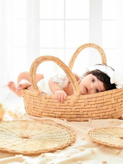 A cozy and classic newborn portrait in a woven basket. The neutral tones and soft fabrics create a warm and secure feeling.