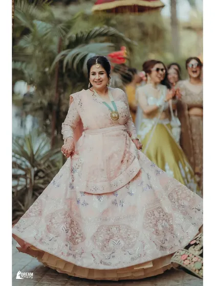 A joyful shot of a wedding guest twirling in her beautiful pink lehenga.