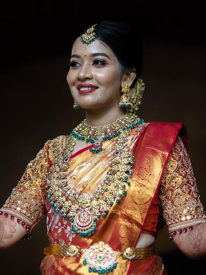 A smiling portrait of our beautiful bride Bhoomika. The intricate choker, long haram, and vaddanam create a complete and stunning bridal look.