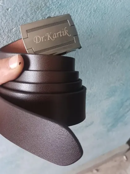 This personalized leather belt has the name and title 'Dr. Kartik' engraved directly onto the buckle, making it a unique and professional accessory.