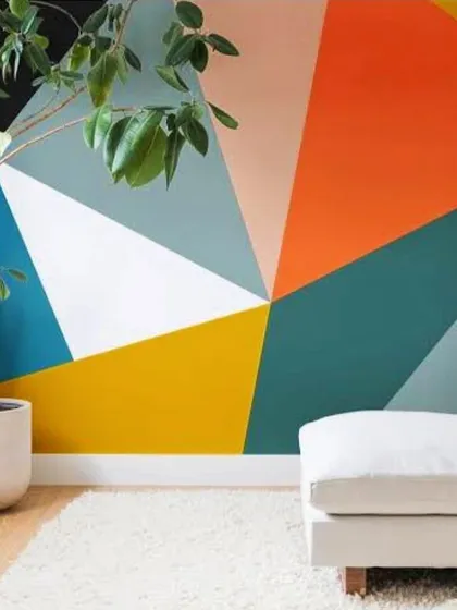 This living room features a dynamic geometric accent wall, using a bold palette of orange, yellow, and teal. This type of colour blocking is a modern way to inject personality and energy into a room, turning a plain wall into a work of art.