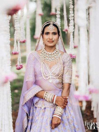 The bride framed by hanging floral decorations. This composition adds depth and a touch of romance to the portrait.