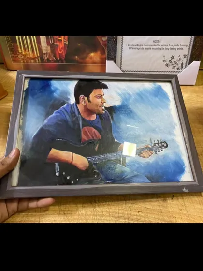 A framed painting of a man playing the guitar, with a cool blue background. This is a great gift for a musician.