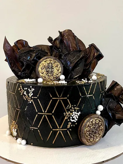 This black and gold design is one of my favorites for its dark, moody elegance. The geometric stenciling, gold-dusted Oreo cookies, and abstract chocolate sails create a stunning, modern texture.