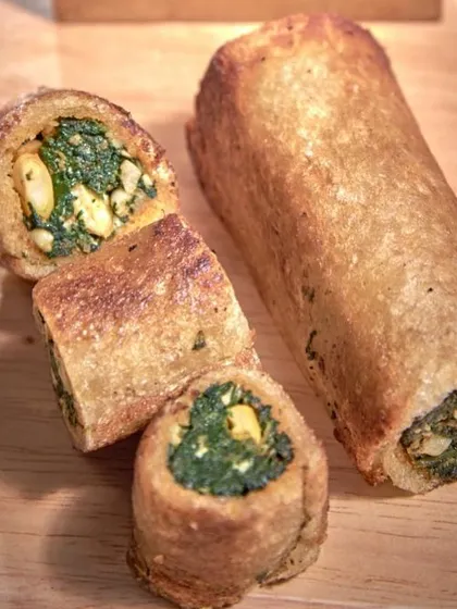 A cross-section of our savory spinach and corn roulade, showcasing the delicious filling inside a crispy, golden-brown exterior.