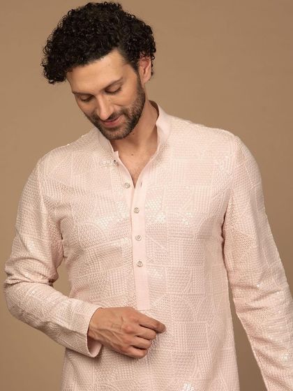 A premium, intricately embroidered luxury kurta in a soft pink hue. The geometric pattern gives it a modern feel, making it a stylish choice for any festive occasion.