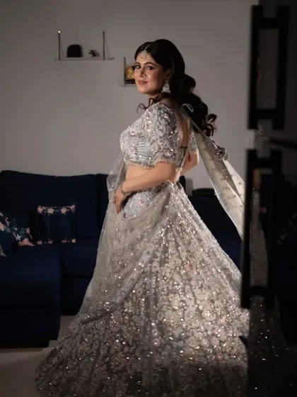 A full-length view showing how the side-swept waves balance the heavily embellished lehenga. This is a perfect look for a bride who wants to shine at her reception.