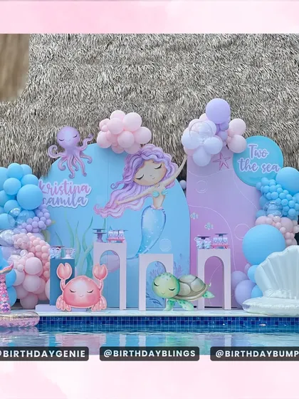 A poolside "Two the Sea" mermaid party, perfectly blending the decor with the location. The blue and purple backdrops and character cutouts create a beautiful scene right by the water.