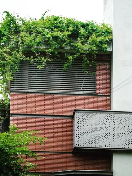 A close-up of the facade of my 'Jenu Goodu' (Beehive) project. The design combines the warmth of brick with the precision of metal louvers and the wildness of a rooftop garden, showcasing a rich material palette.