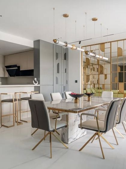 An open-concept layout connecting the kitchen, dining, and living areas. A custom brass-detailed partition provides a visual screen while allowing light and conversation to flow freely, making the space perfect for entertaining.