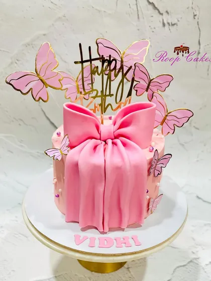 A beautiful bow cake, featuring a large pink fondant bow and fluttering butterflies for a whimsical touch.