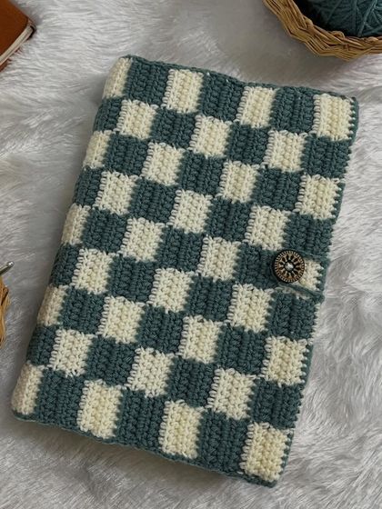 A top-down view of the checkered book cover. The pattern is created using a technique called tapestry crochet.