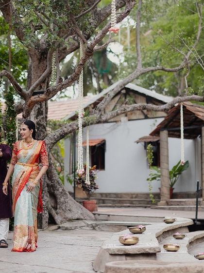 A couple walks through the courtyard, framed by ancient trees and a decorated swing, a perfect wide shot to capture the scale and beauty of the property.