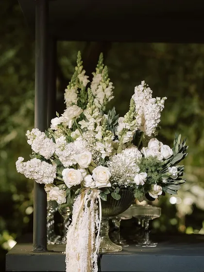 A beautiful centerpiece of white roses, snapdragons, and baby's breath in a classic glass vase, perfect for an elegant evening affair.