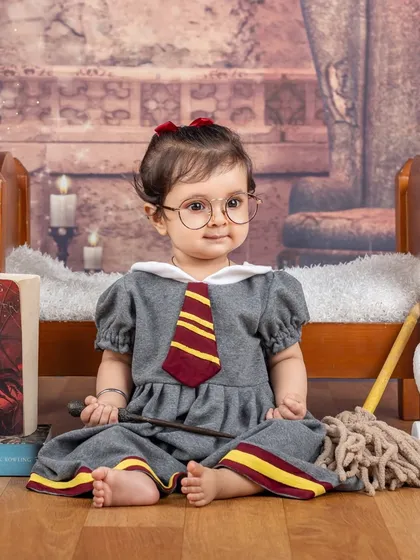 A sweet and serious little witch, holding her glasses and wand. The details in her dress and the backdrop make this Harry Potter portrait so special.