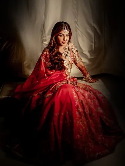 Seated with her lehenga spread around her, this shot is pure royalty. The dramatic lighting and rich colors create a powerful and unforgettable bridal portrait.