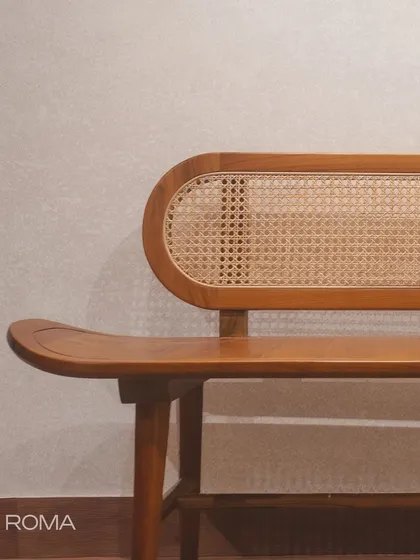 The 'Roma' bench, with its distinctive pill-shaped rattan backrest and gracefully curved seat. It's a masterpiece of craftsmanship.