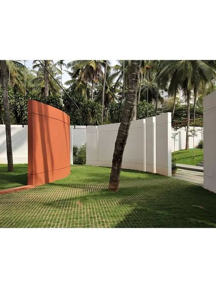 The Akriti Experience Centre, where freestanding walls in white and terracotta create a sculptural pathway through a grove of palm trees.