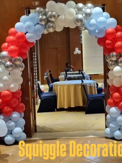 A red, white, and blue balloon arch for a 'Cars' themed birthday party, complete with a personalized welcome sign.