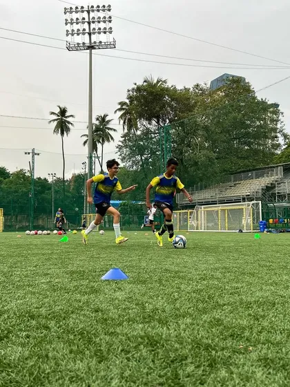 Two young footballers navigate a cone drill, focusing on close control and agility. This image illustrates how our training challenges players to change and improve their game.