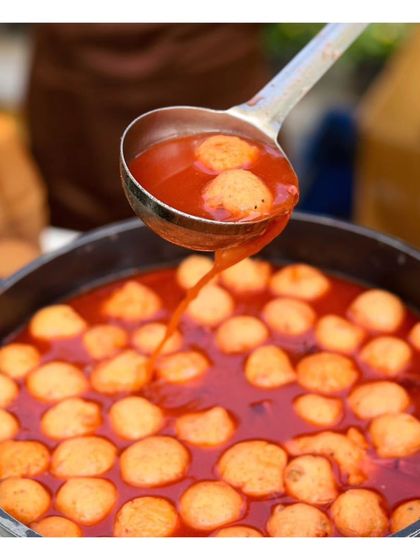 A close-up of Kanji Vada, a traditional Rajasthani delicacy, being served from a large pot, perfect for a vegetarian wedding menu.