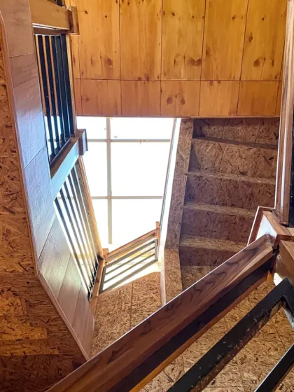 Looking up through the central staircase, a skylight floods the core of the house with natural light, making the space feel open and bright despite its wooded setting.