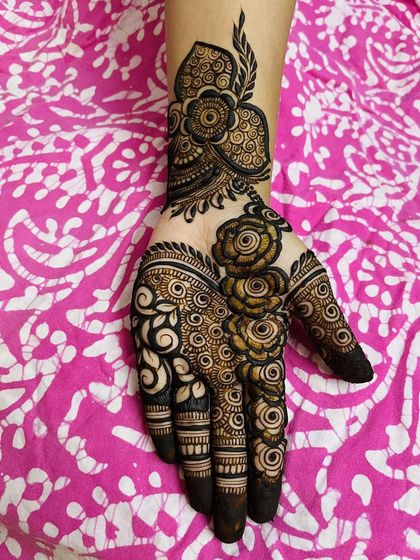 This party-style mehendi features a bold floral vine that trails down the hand. The combination of thick and thin lines gives it depth and makes it incredibly eye-catching.