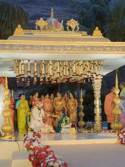 A traditional South Indian mandap, elegant in its design with gold pillars and floral hangings, set against the scenic backdrop of Della Resorts.