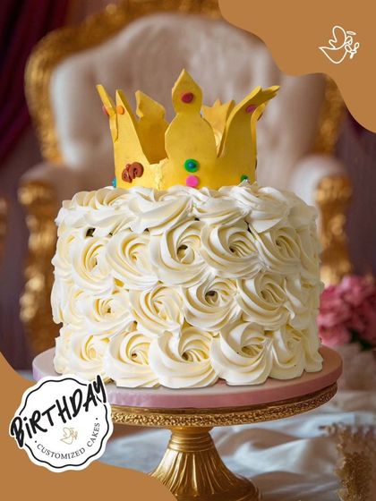 A regal cake featuring a bed of white buttercream roses topped with a golden crown. This design is simple yet elegant, perfect for celebrating the queen in your life on her special day.