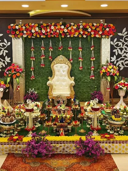 A Half-Saree function setup with a "tree of life" backdrop. The plate decoration is colorful and arranged symmetrically.