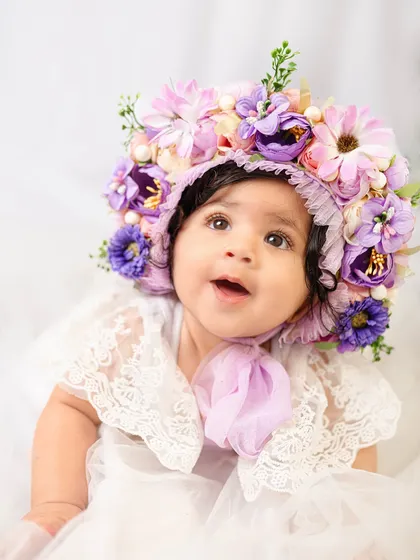 A look of pure wonder from an eight-month-old in a stunning purple and pink floral bonnet. The details in this accessory are just magical.