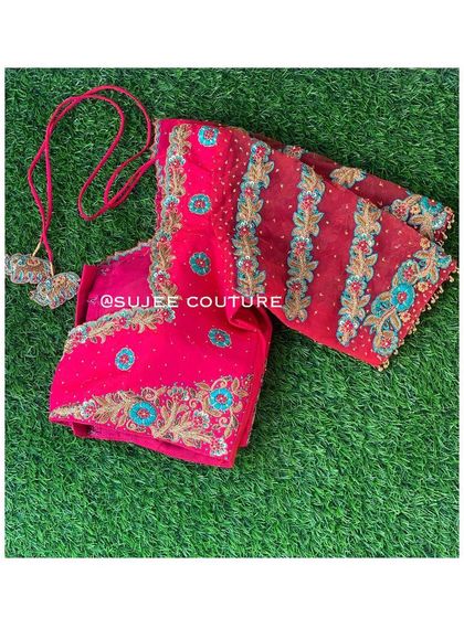 A folded view of the pink blouse, highlighting the striped pattern on the sheer sleeves and the intricate embroidery work.