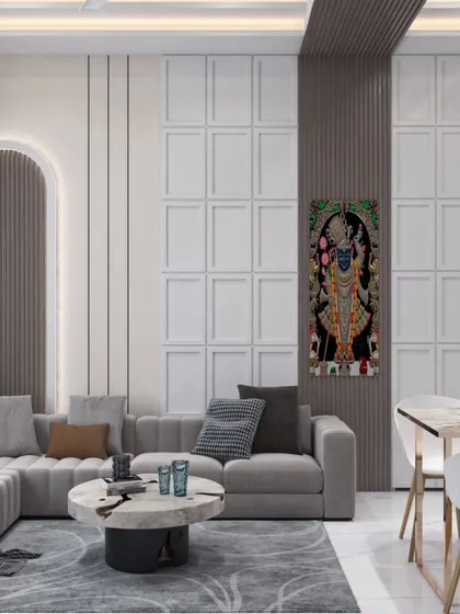 In this living room, we blended contemporary design with traditional Indian art. The walls feature a sophisticated combination of fluted panels and classic moulding, creating a textured backdrop for the serene Shrinathji painting. This space demonstrates our ability to create modern homes that honor cultural heritage and provide a sense of peace.