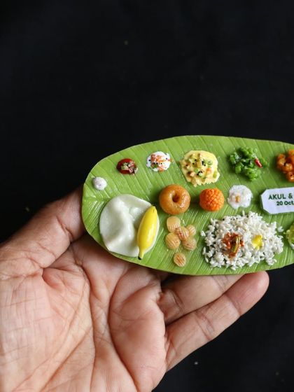 A close-up of a personalized wedding favor, a South Indian meal magnet that serves as a unique and memorable gift.