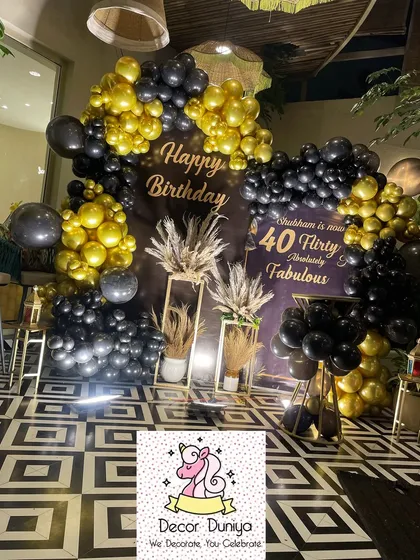 Here’s a look at a chic and modern 40th birthday celebration we designed. The decor features a bold black and gold balloon arch, a custom backdrop, and elegant pampas grass arrangements for a sophisticated party vibe.
